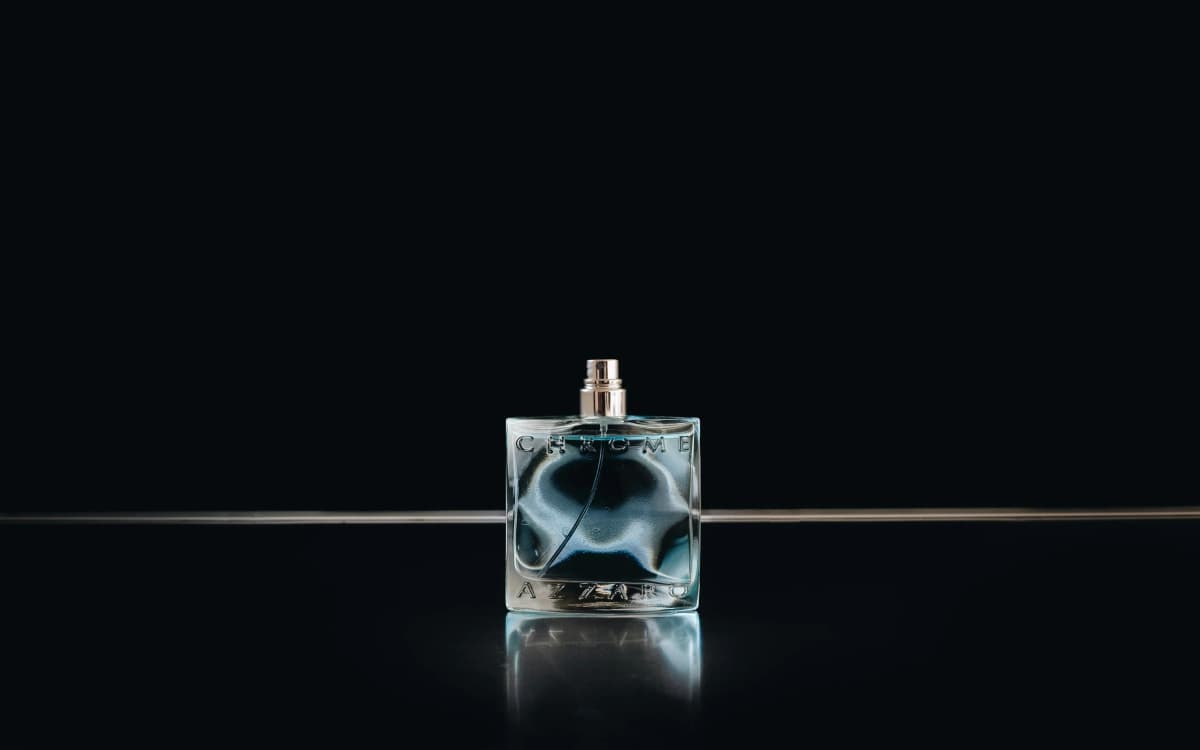 A clear fragrance bottle on a black surface